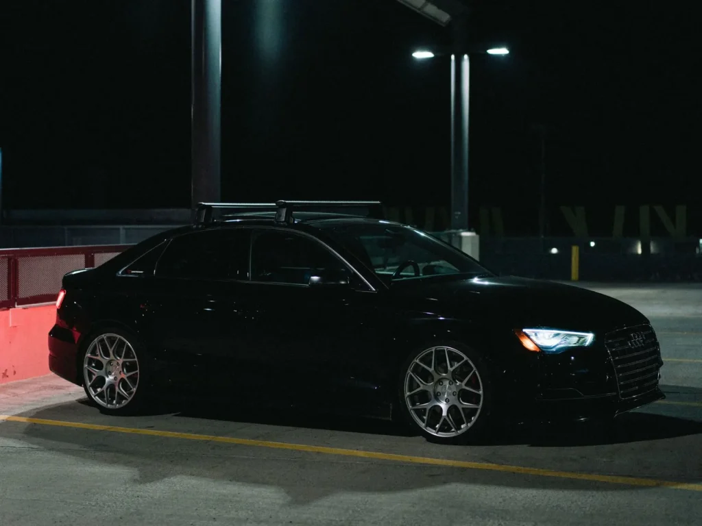 Black saloon parked on an empty car park deck at night, headlights on