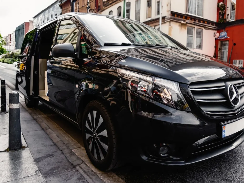 Black passenger van with its sliding door open beside a city pavement